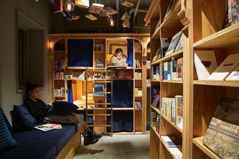 Timber shelving of books with a sleeping recess set into the wall behind